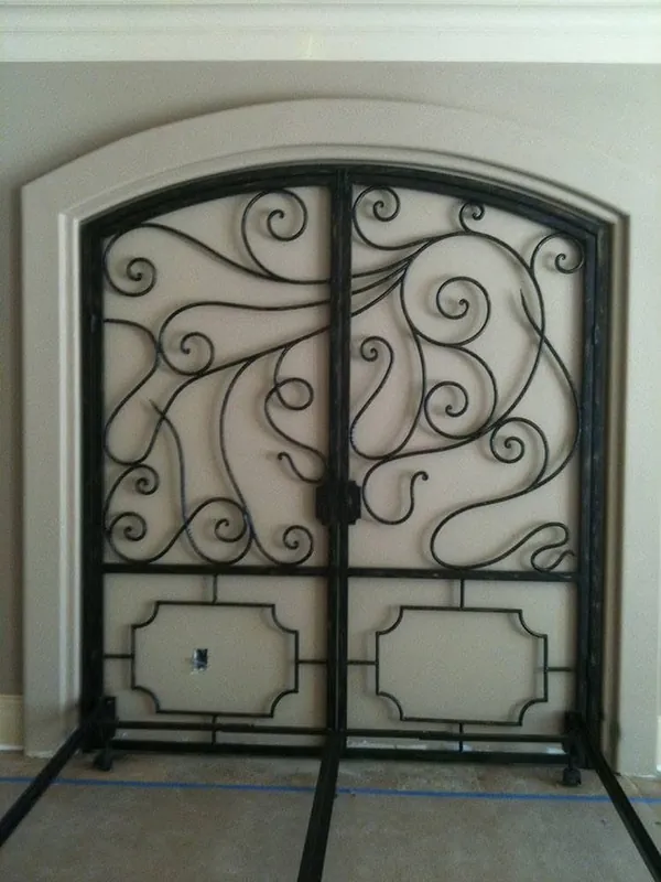 An arched iron door with curved lines and ornaments.