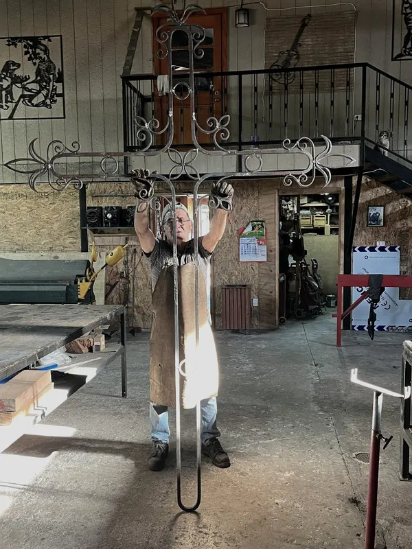 Raúl Abarca holds an iron crucifix in his workshop.